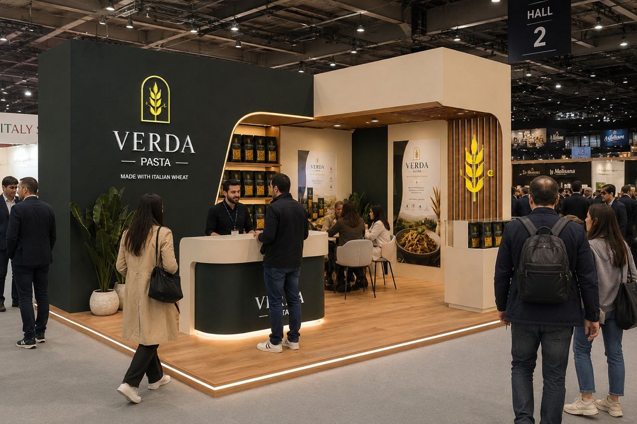 VERDA pasta exhibition stand with dark olive brand wall, warm canopy and active visitor reception